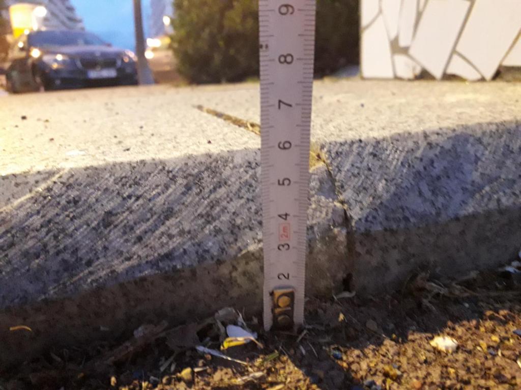 Primer plano de un metro midiendo un bordillo en la calle, tiene una altura de 6 cm.